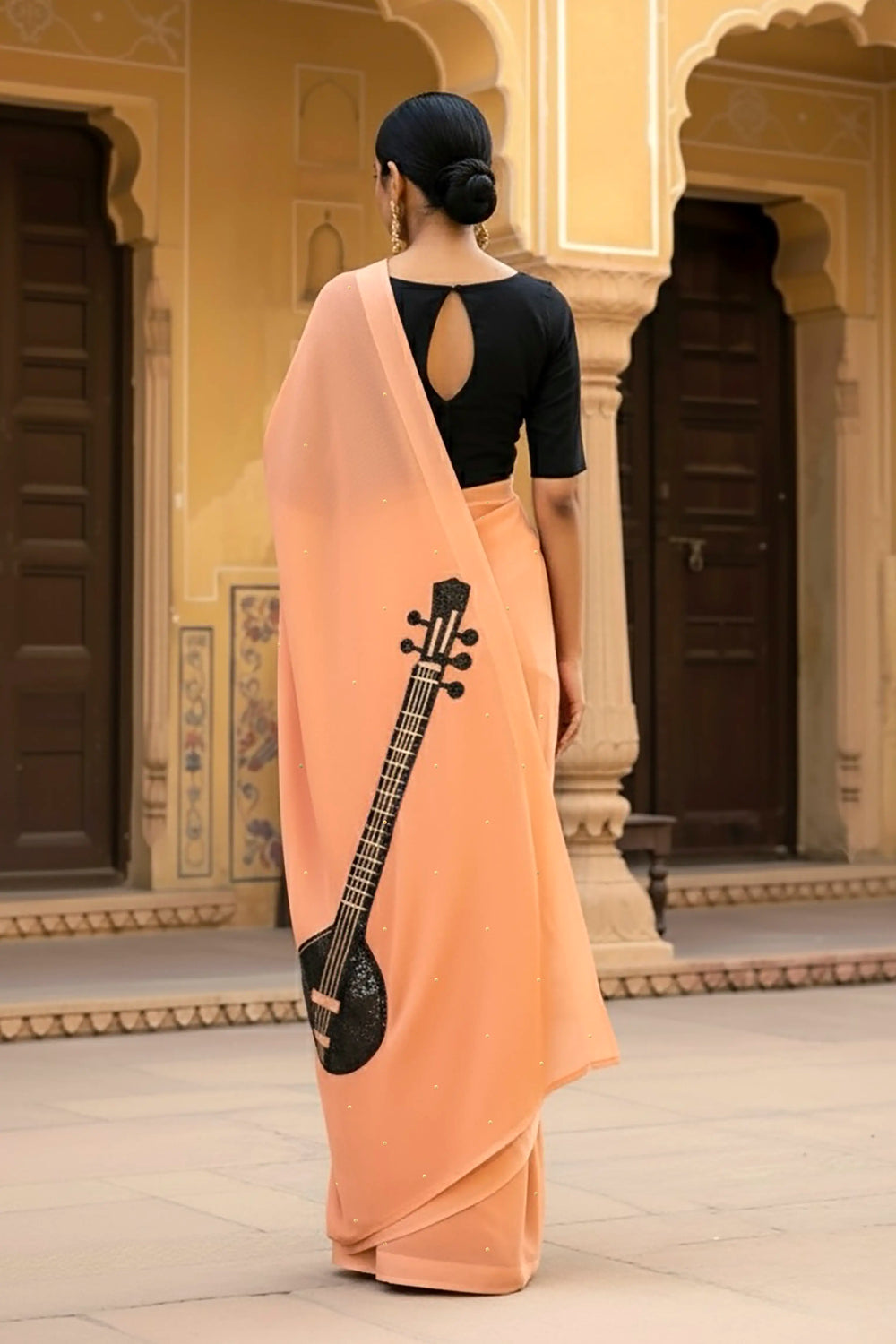 A woman in peach saree embellished with Sitar motif by Umaid Couture