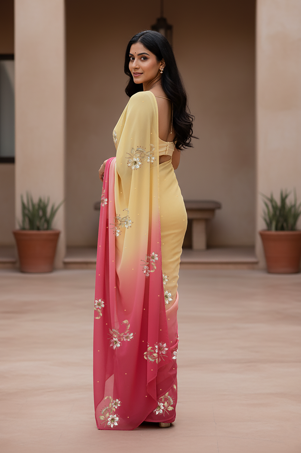 Woman wearing a yellow and pink saree  by Umaid Couture with floral patterns indoors.