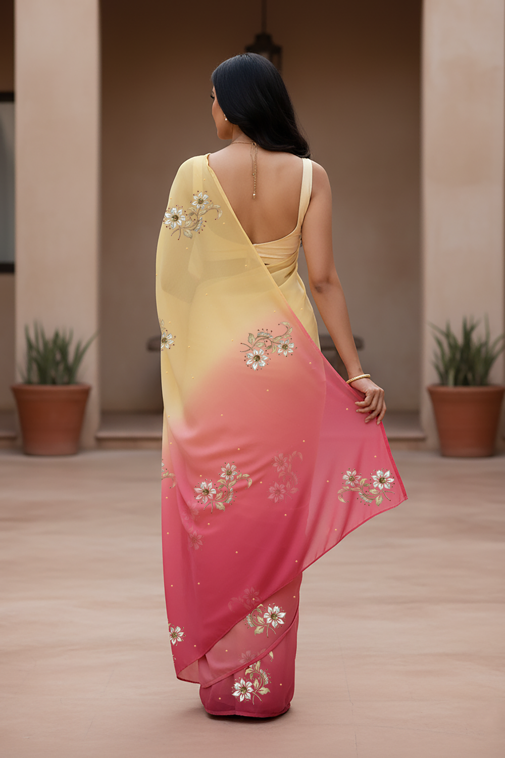 Woman wearing a yellow and pink saree  by Umaid Couture with floral patterns indoors.
