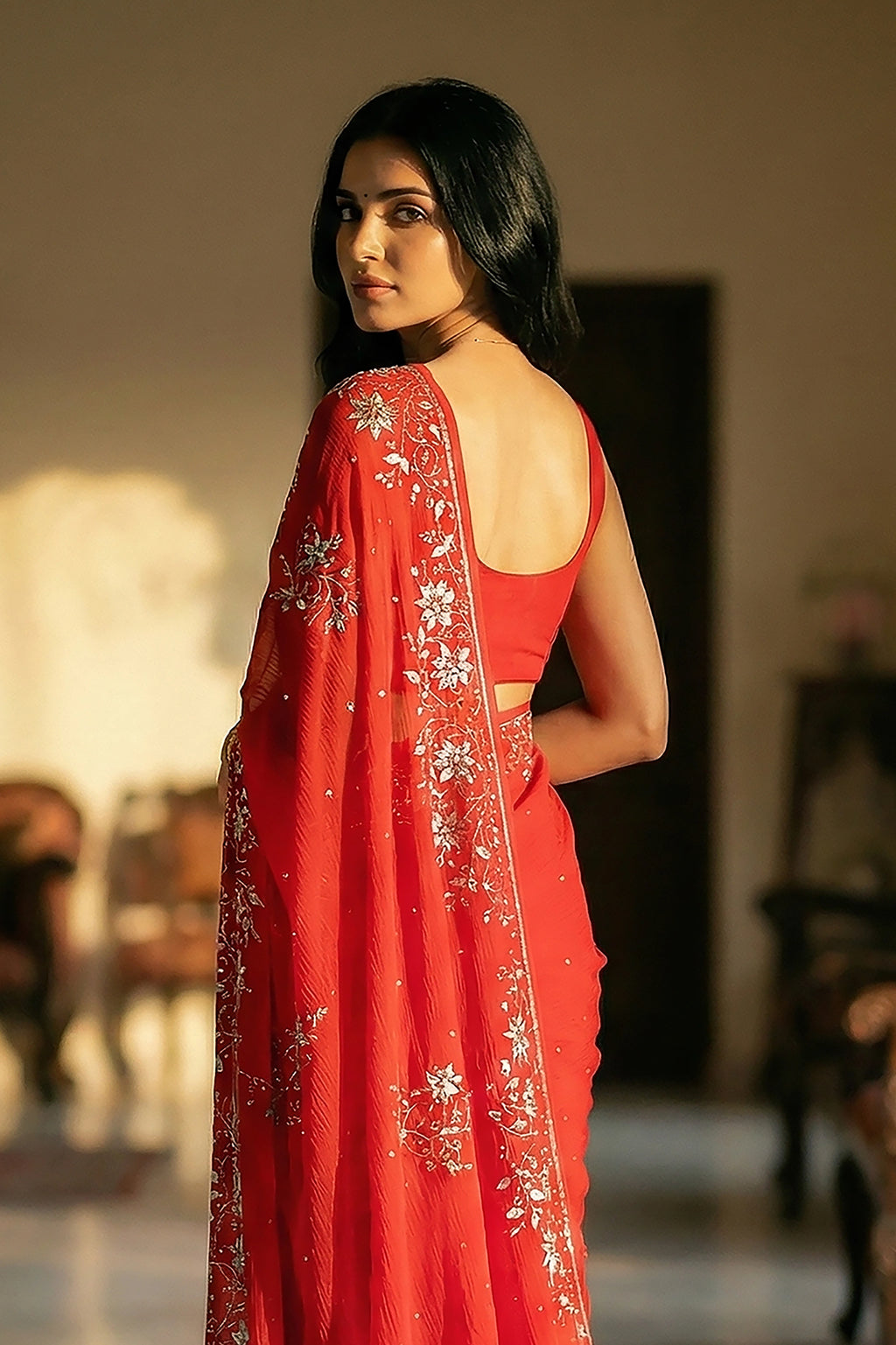 Woman in mulberry red saree with jasmine floral vines border on saree made by umaid couture.