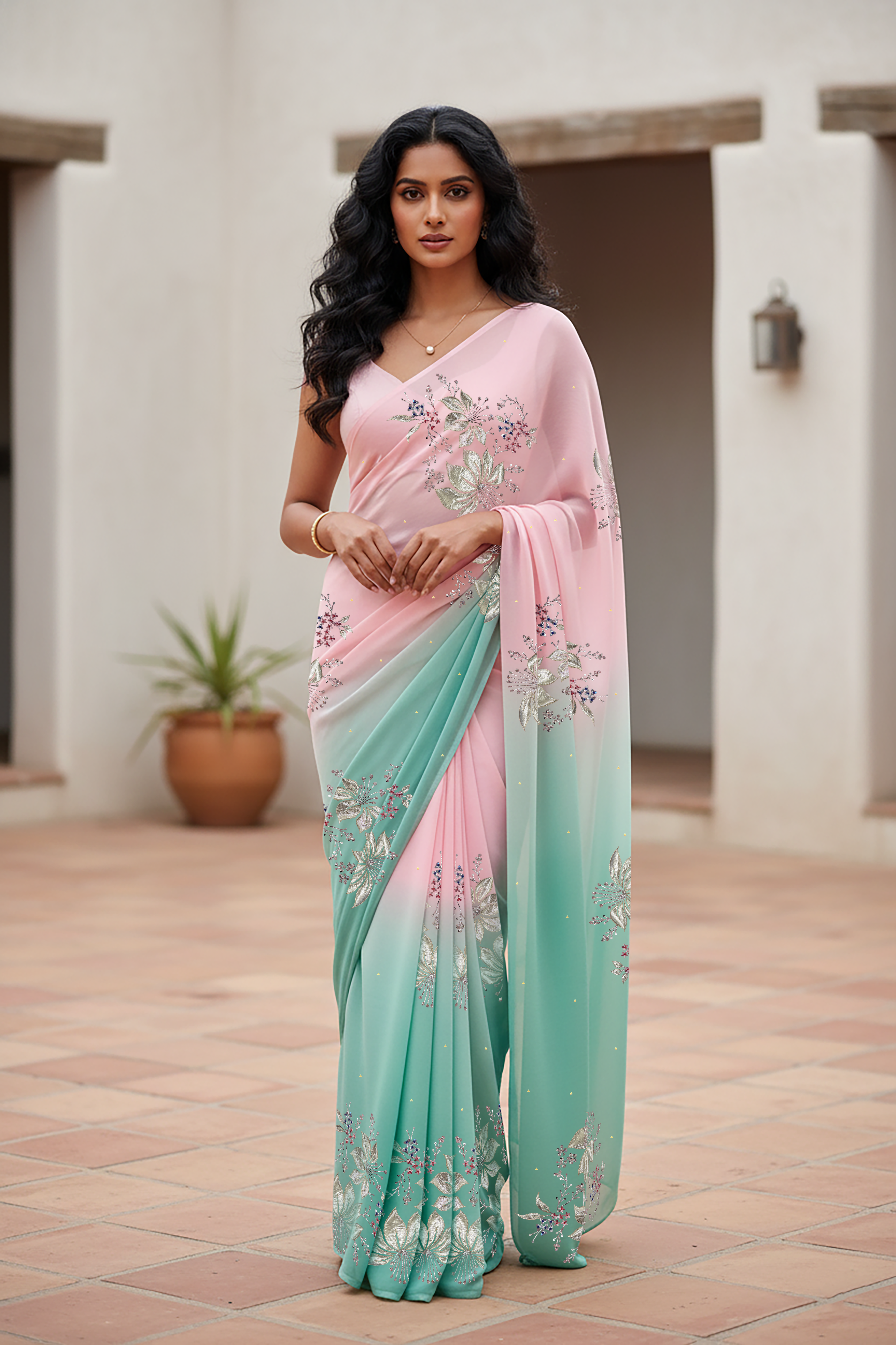 Woman wearing a gradient pastel pink and sea green chiffon saree by Umaid Couture, standing in a minimal courtyard.