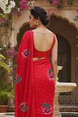 A model wearing a red peacock motifs saree by Umaid Couture standing in a Garden Courtyard.