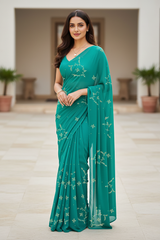 Woman wearing a teal saree with Gota patti gulmohar motifs in an indoor setting. The saree is by Umaid couture