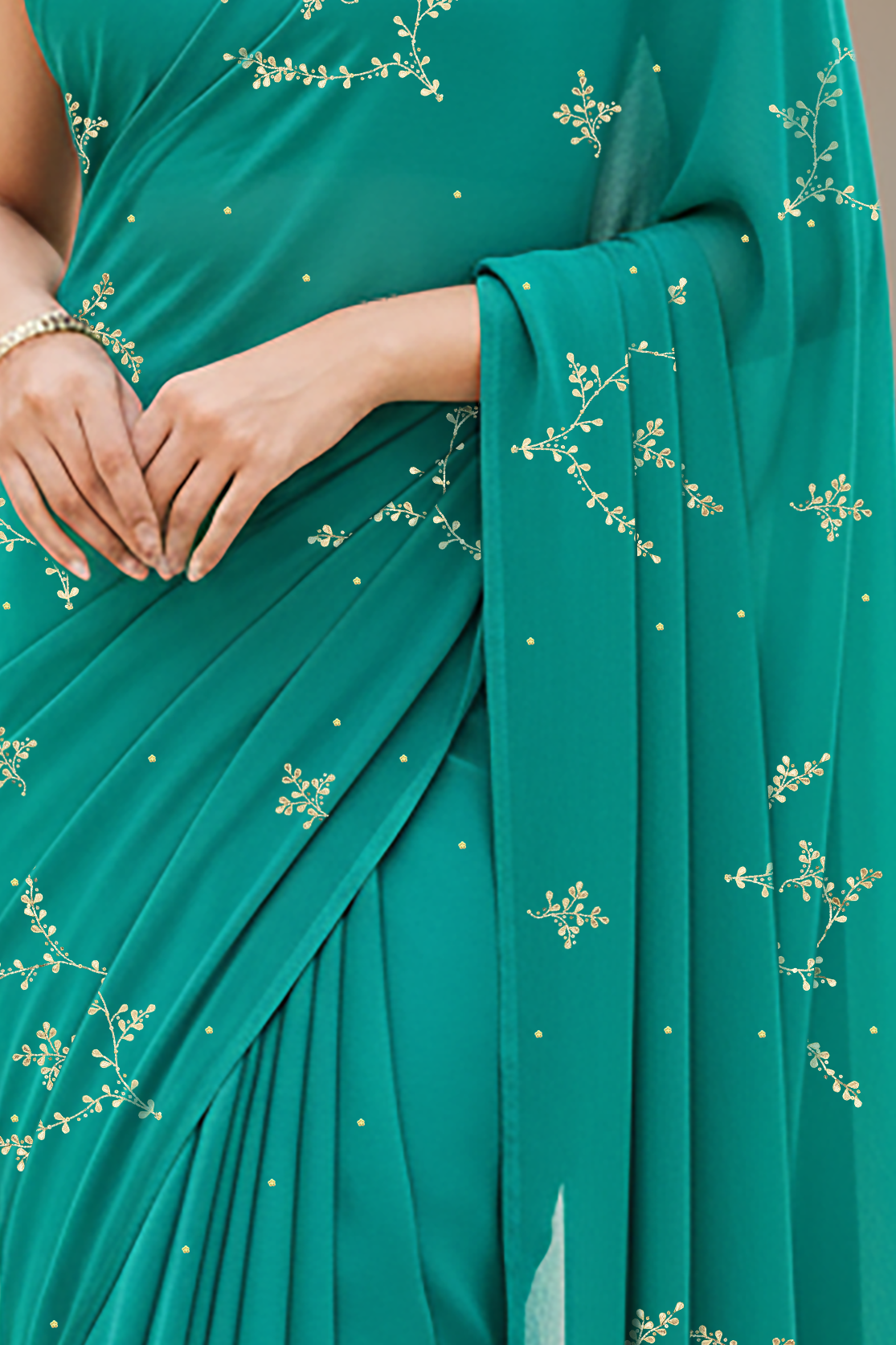 Teal saree with floral patterns worn by a person, blurred background