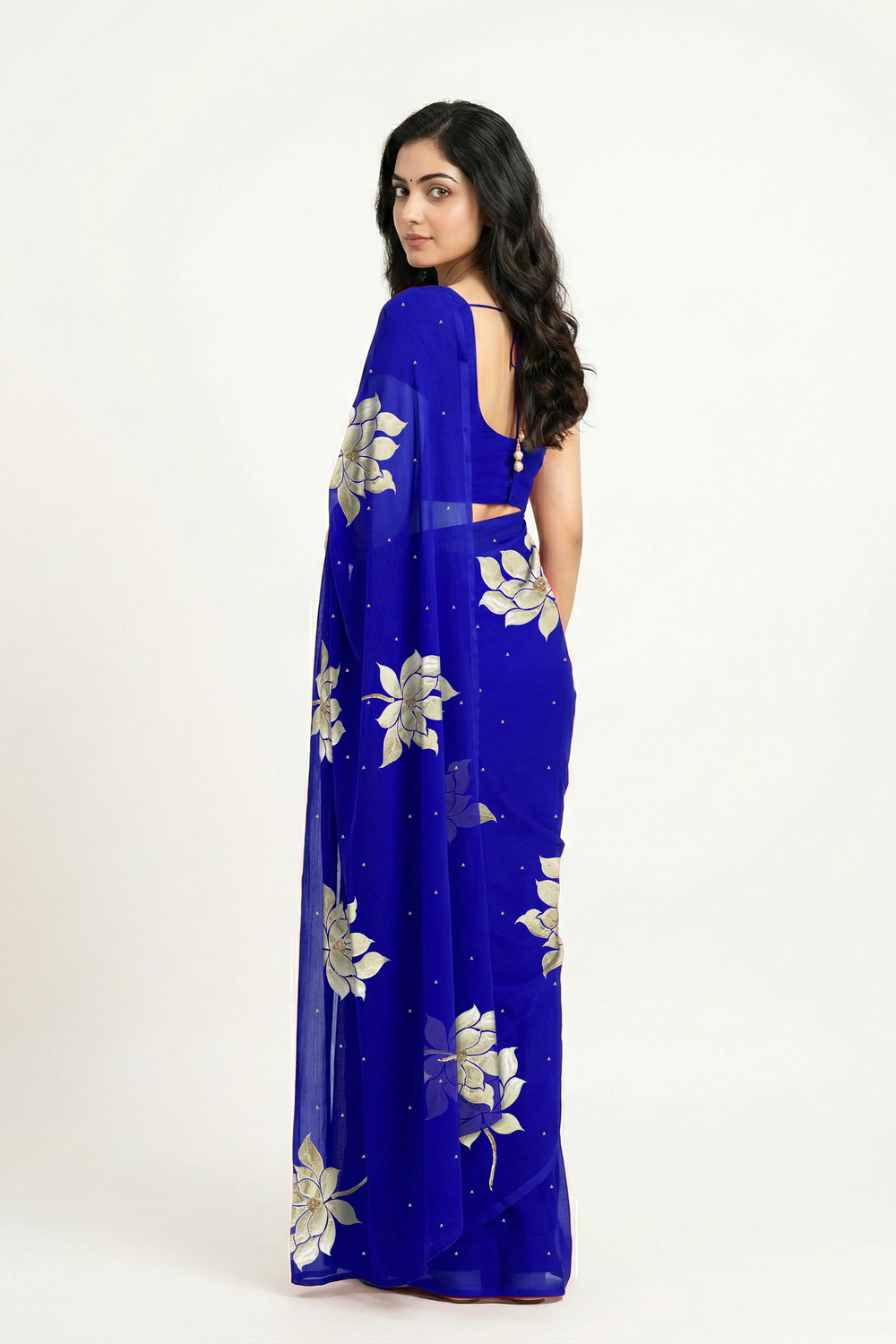 An Indian woman in blue Padma Saree embellished  with Blooming lotus flowers made of Gota, Zari & sequins by craft of Aari-Zardosi, a product of Umaid Couture