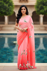 An Indian woman standing in a garden courtyard wearing a gradient of pink chiffon saree embellished with green and sliver sequin of l parrot siting in heritage style window motifs by Umaid Couture.  

