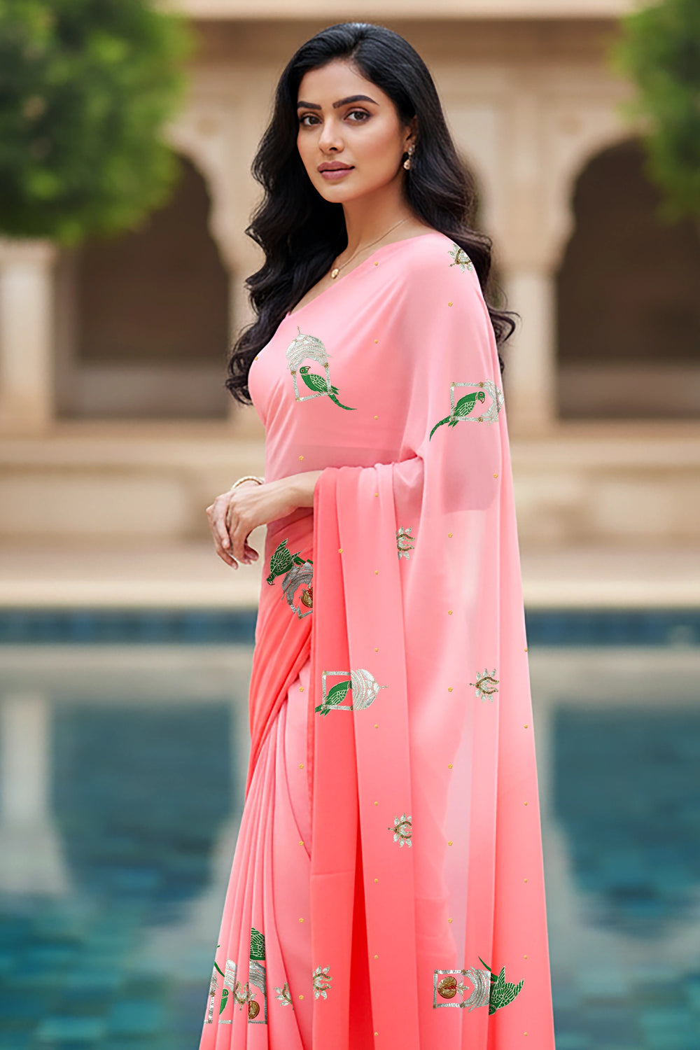 An Indian woman standing in a garden courtyard wearing a gradient of pink chiffon saree embellished with green and sliver sequin of l parrot siting in heritage style window motifs by Umaid Couture.  
