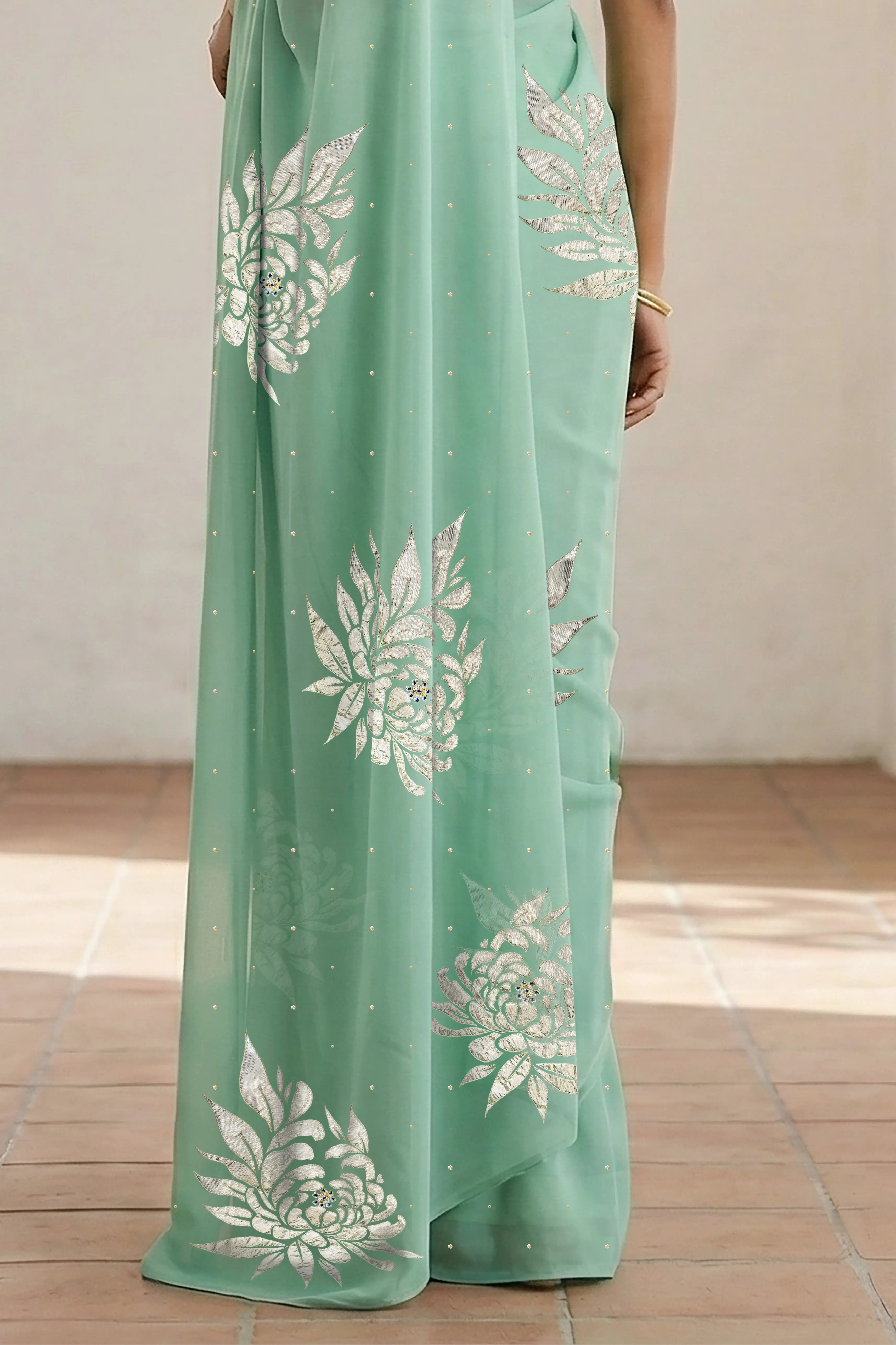 Woman wearing a light green saree with beautiful magnolia flower motif on it made by umaid couture.