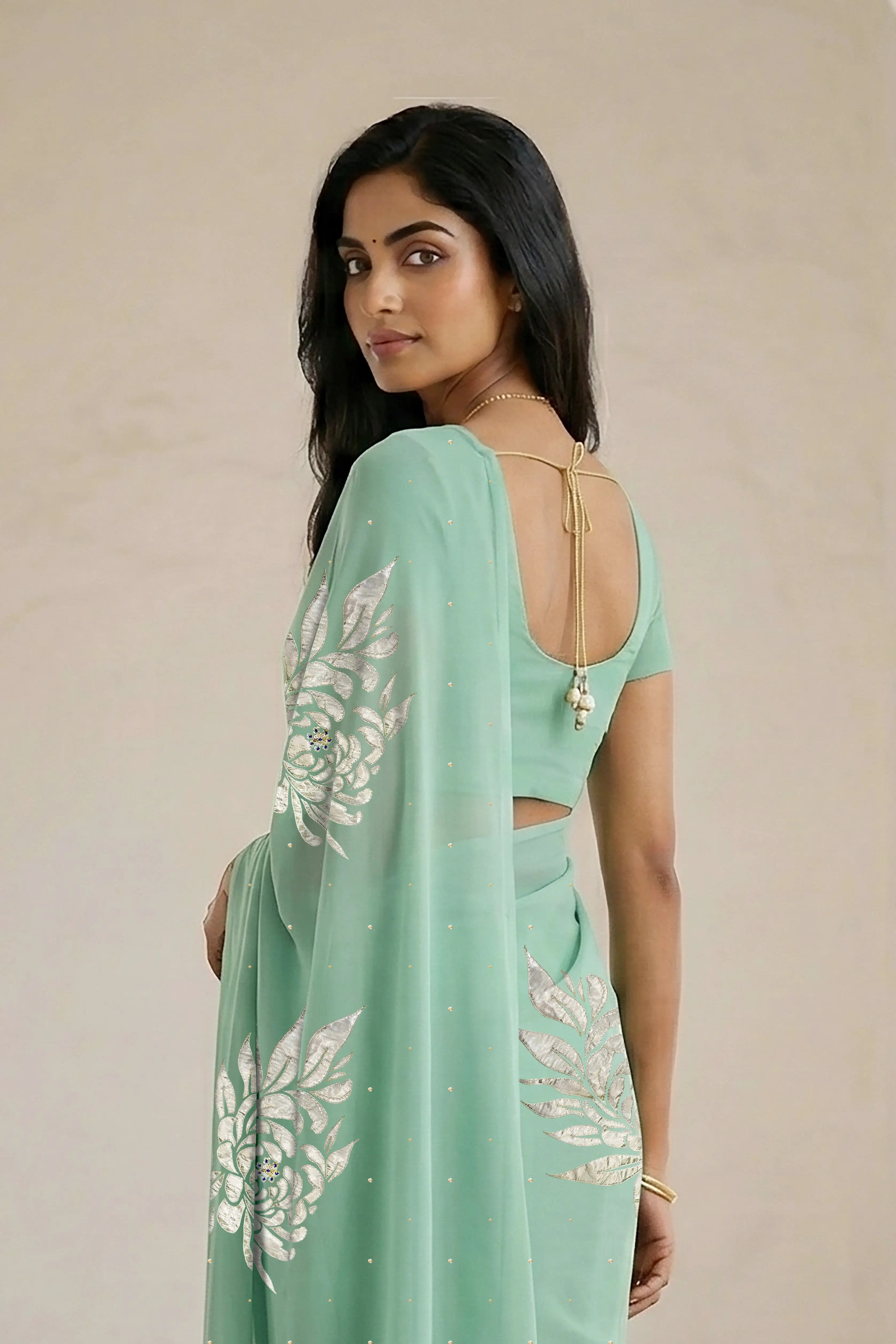 Woman wearing a light green saree with beautiful magnolia flower motif on it made by umaid couture.