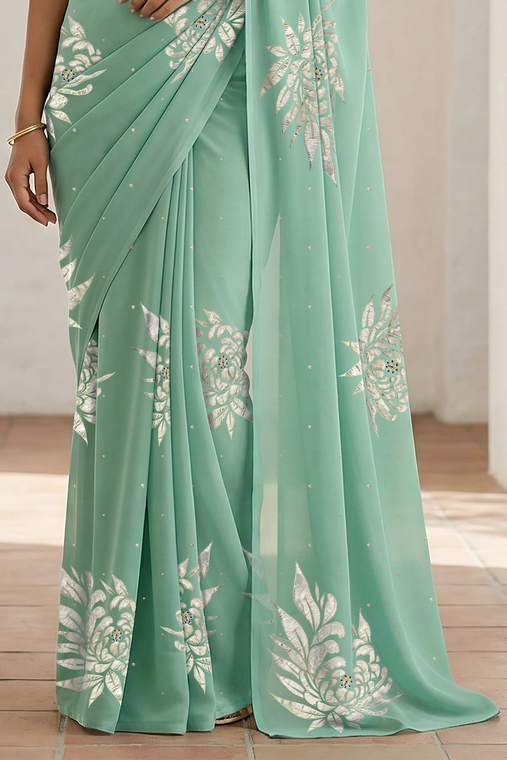 Woman wearing a light green saree with beautiful magnolia flower motif on it made by umaid couture.
