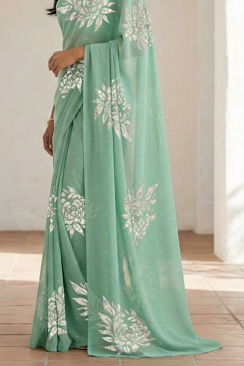 Woman wearing a light green saree with beautiful magnolia flower motif on it made by umaid couture.