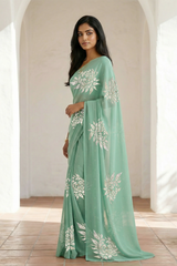 Woman wearing a light green saree with beautiful magnolia flower motif on it made by umaid couture.