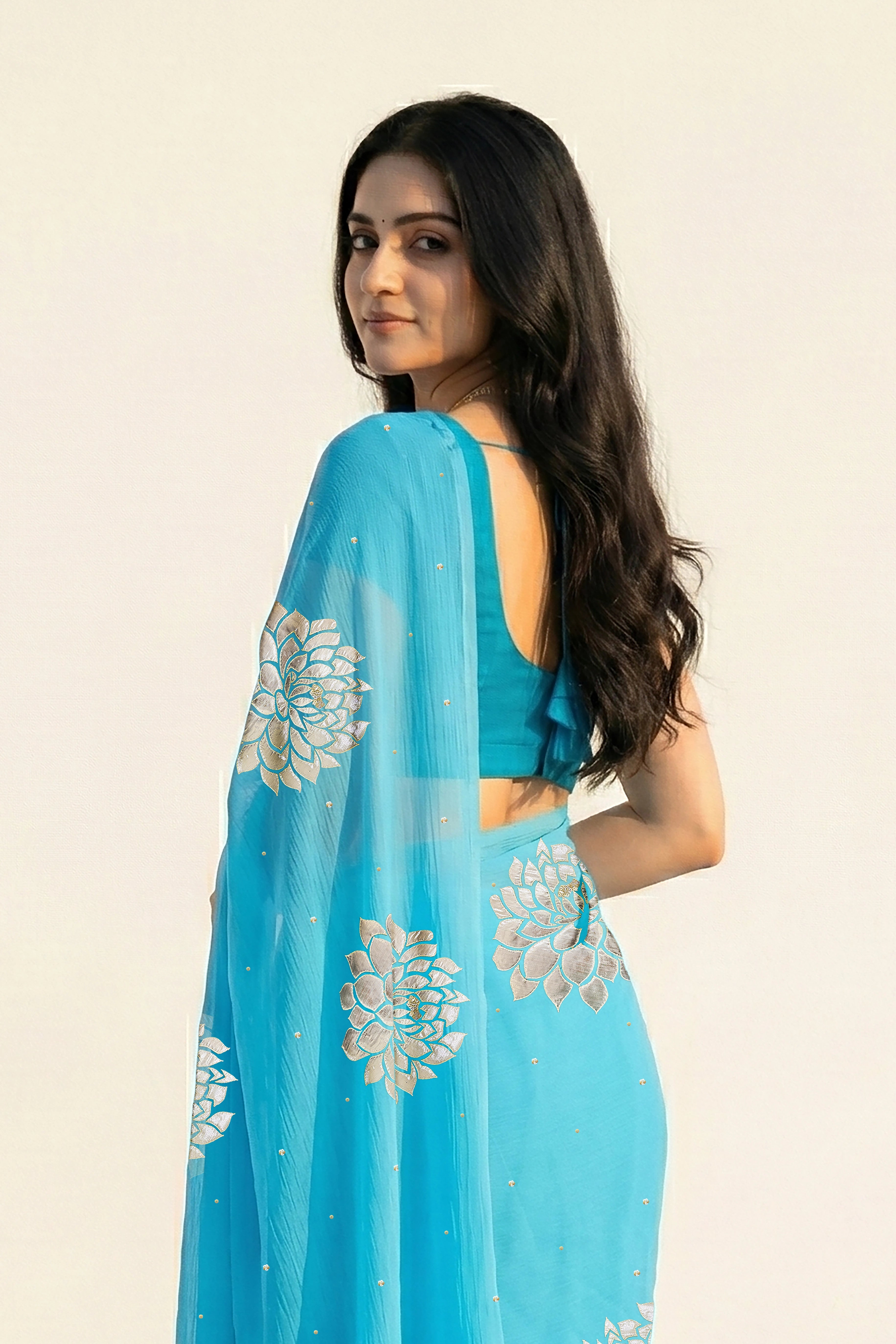 An Indian woman in Middle Blue Dahlia Saree embellished with Blooming Dahlia flowers made of Gota, Zari & sequins by craft of Aari-Zardosi, a product of Umaid Couture