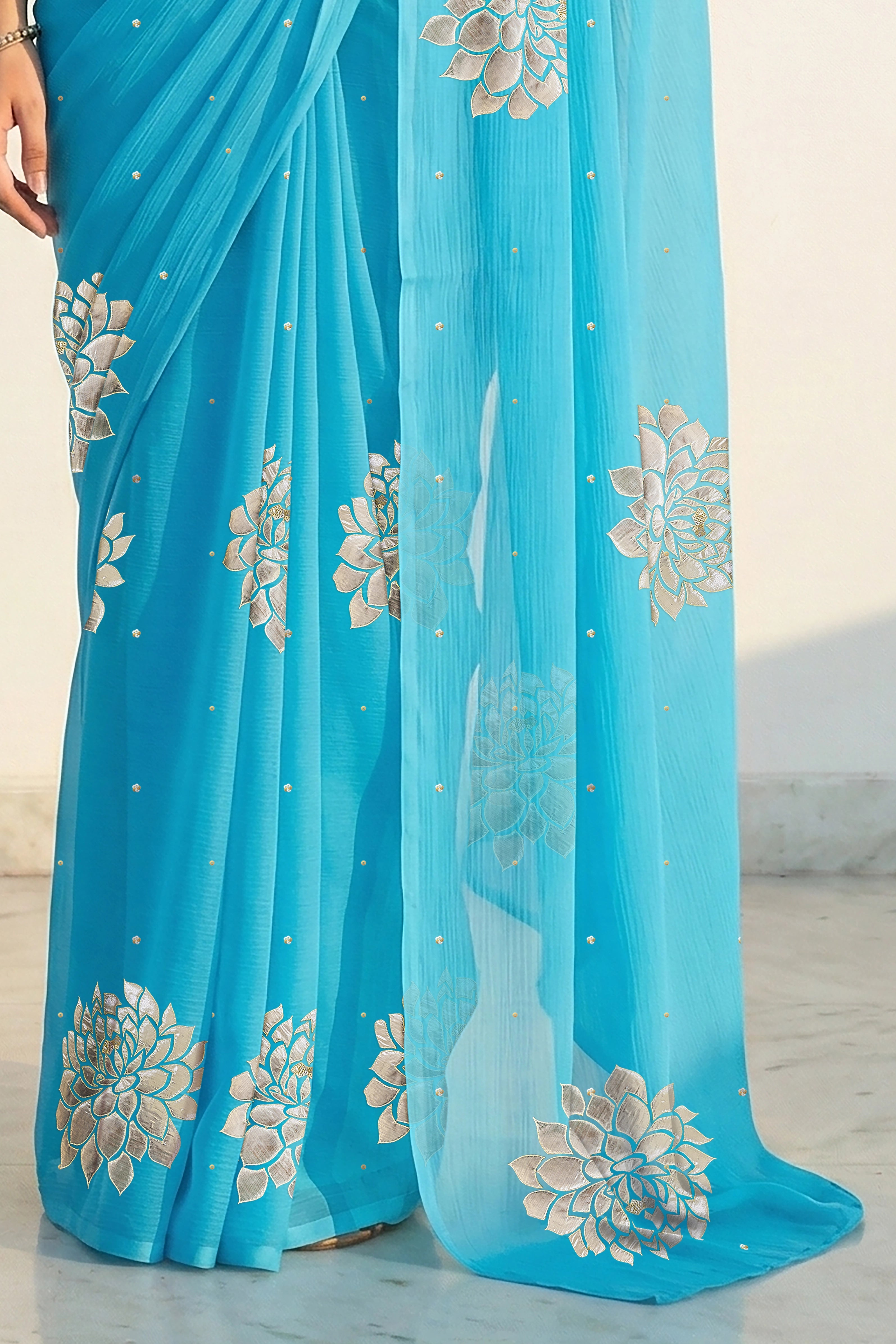 An Indian woman in Middle Blue Dahlia Saree embellished with Blooming Dahlia flowers made of Gota, Zari & sequins by craft of Aari-Zardosi, a product of Umaid Couture