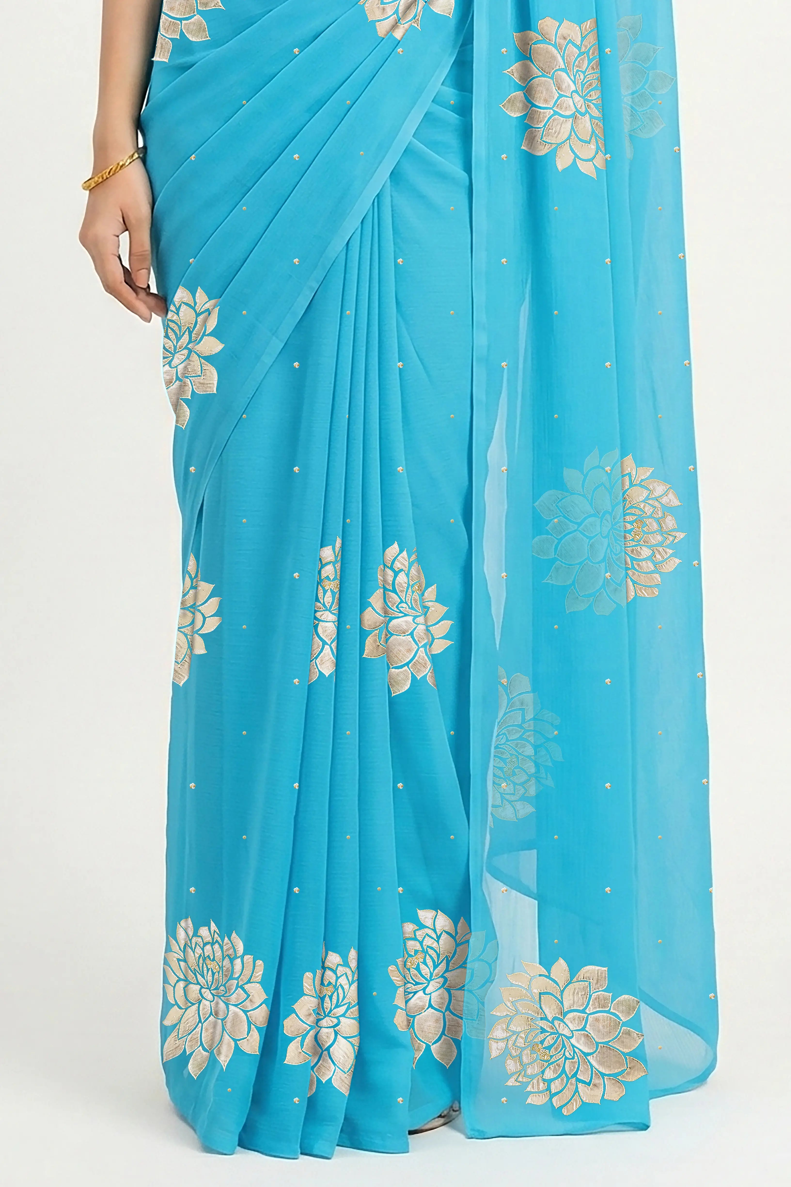 An Indian woman in Middle Blue Dahlia Saree embellished with Blooming Dahlia flowers made of Gota, Zari & sequins by craft of Aari-Zardosi, a product of Umaid Couture