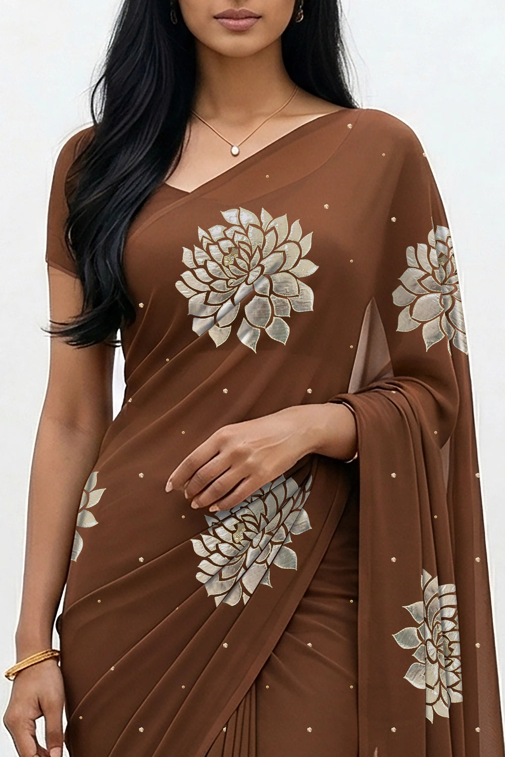 An Indian woman standing in a minimal white courtyard wearing a chocolate brown chiffon saree embellished with golden and sliver sequin of Dahlia flower motifs by Umaid Couture.  
