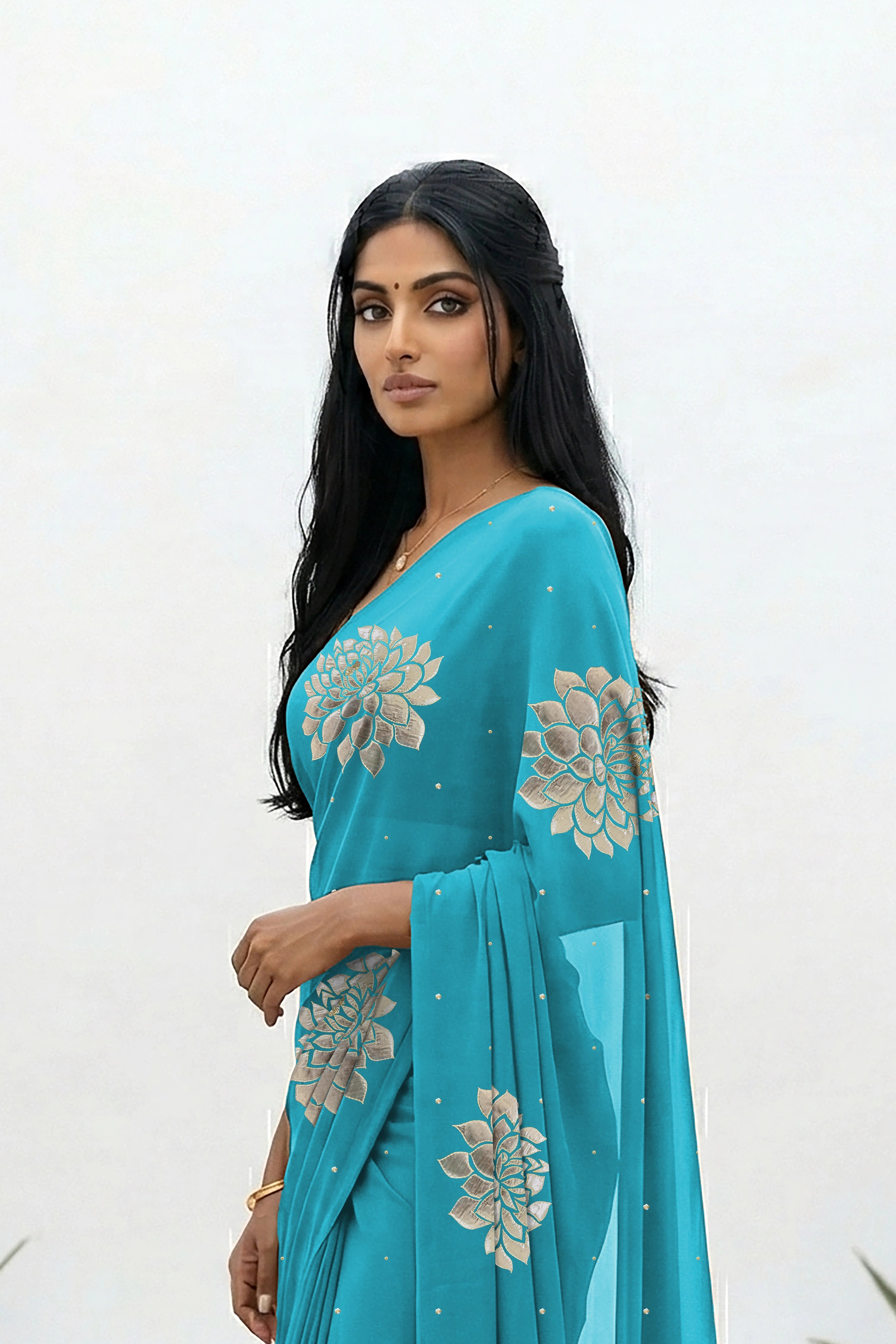 An Indian woman standing in a minimal white courtyard wearing a middle blue chiffon saree embellished with golden and sliver sequin of Dahlia flower motifs by Umaid Couture.  
