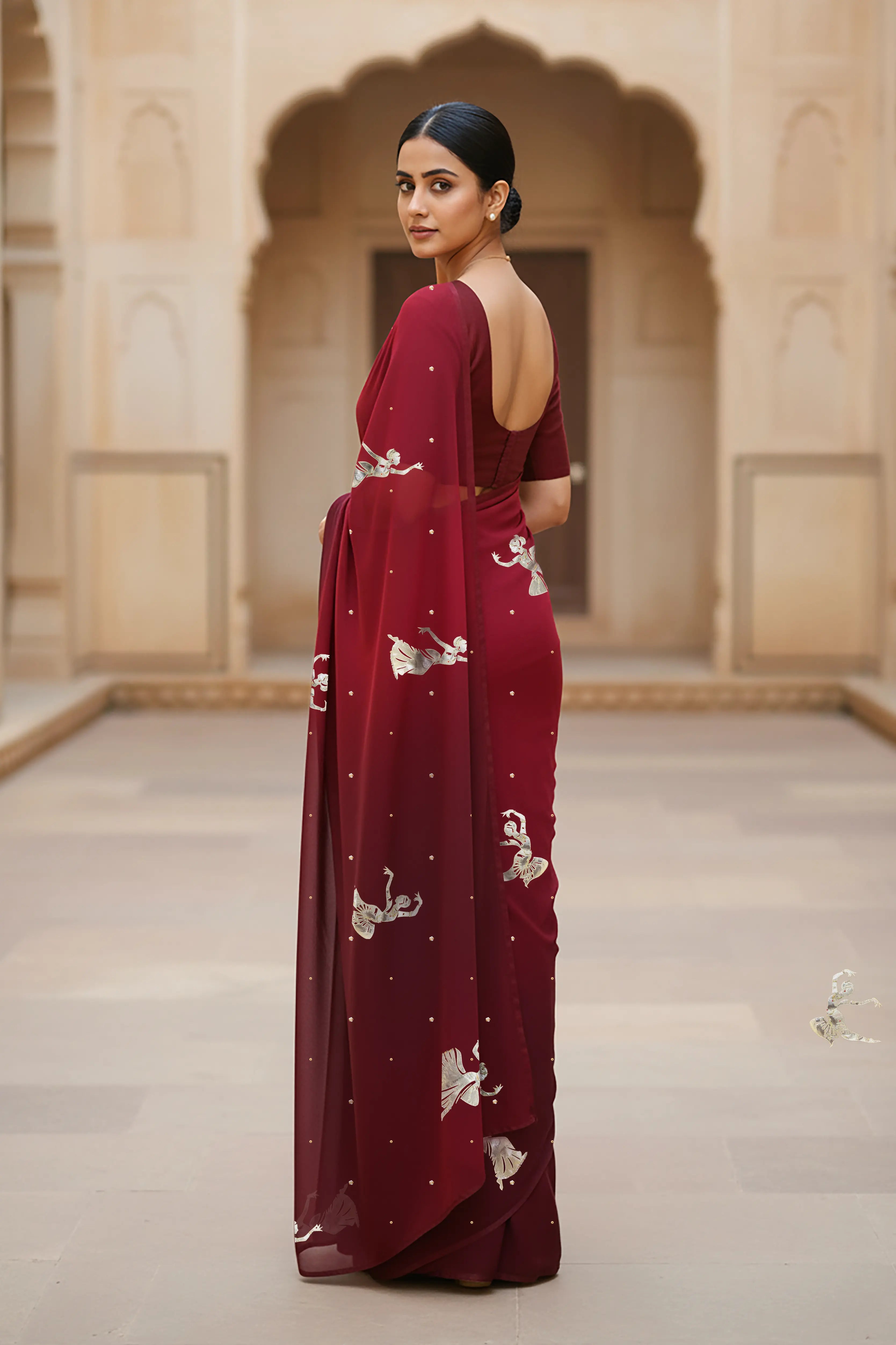 woman standing wearing wine red hue mulberry chiffon silk saree with kathak dance motifs on it designed bt umaid couture.