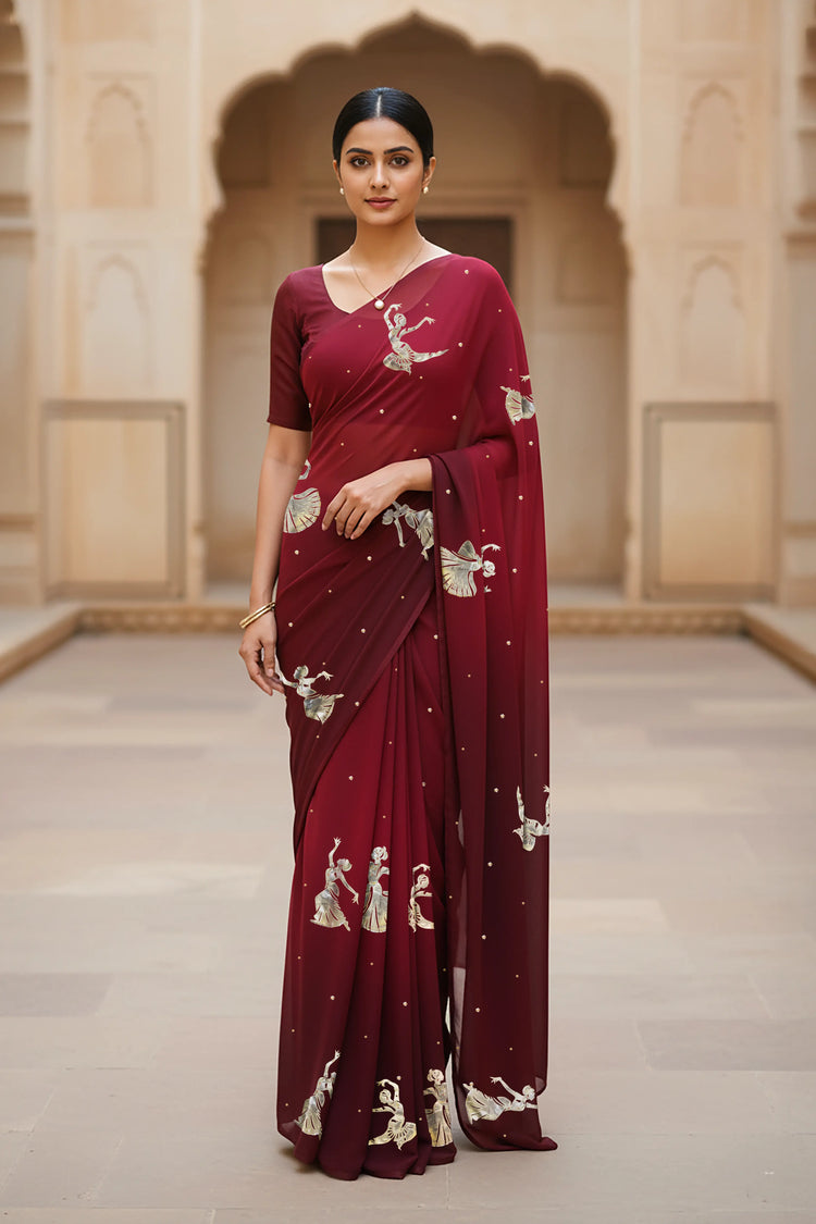 woman standing wearing wine red hue mulberry chiffon silk saree with kathak dance motifs on it designed bt umaid couture.
