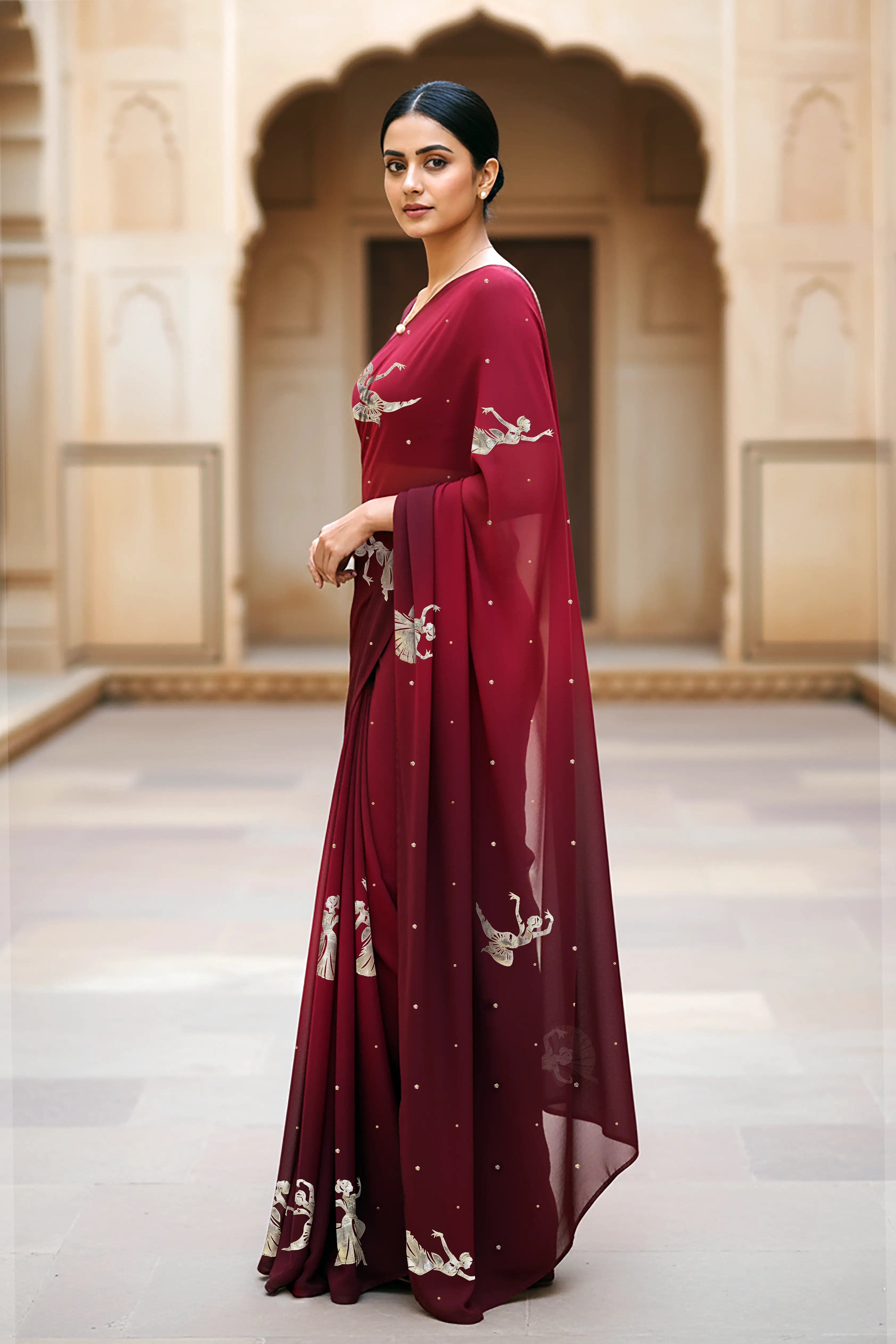 woman standing wearing wine red hue mulberry chiffon silk saree with kathak dance motifs on it designed bt umaid couture.