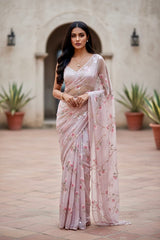Woman in a light pink saree with floral  sequins patterns standing in an outdoor setting. The saree is by Umaid Couture