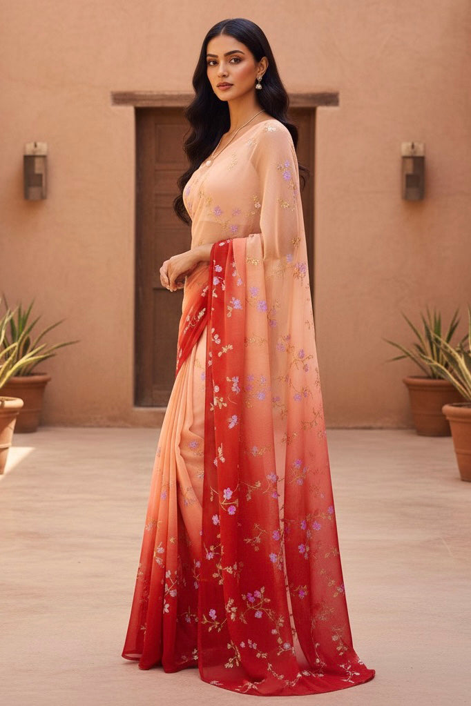 Woman wearing a peach and red saree with floral patterns against a beige wall. Product by Umaid Couture.