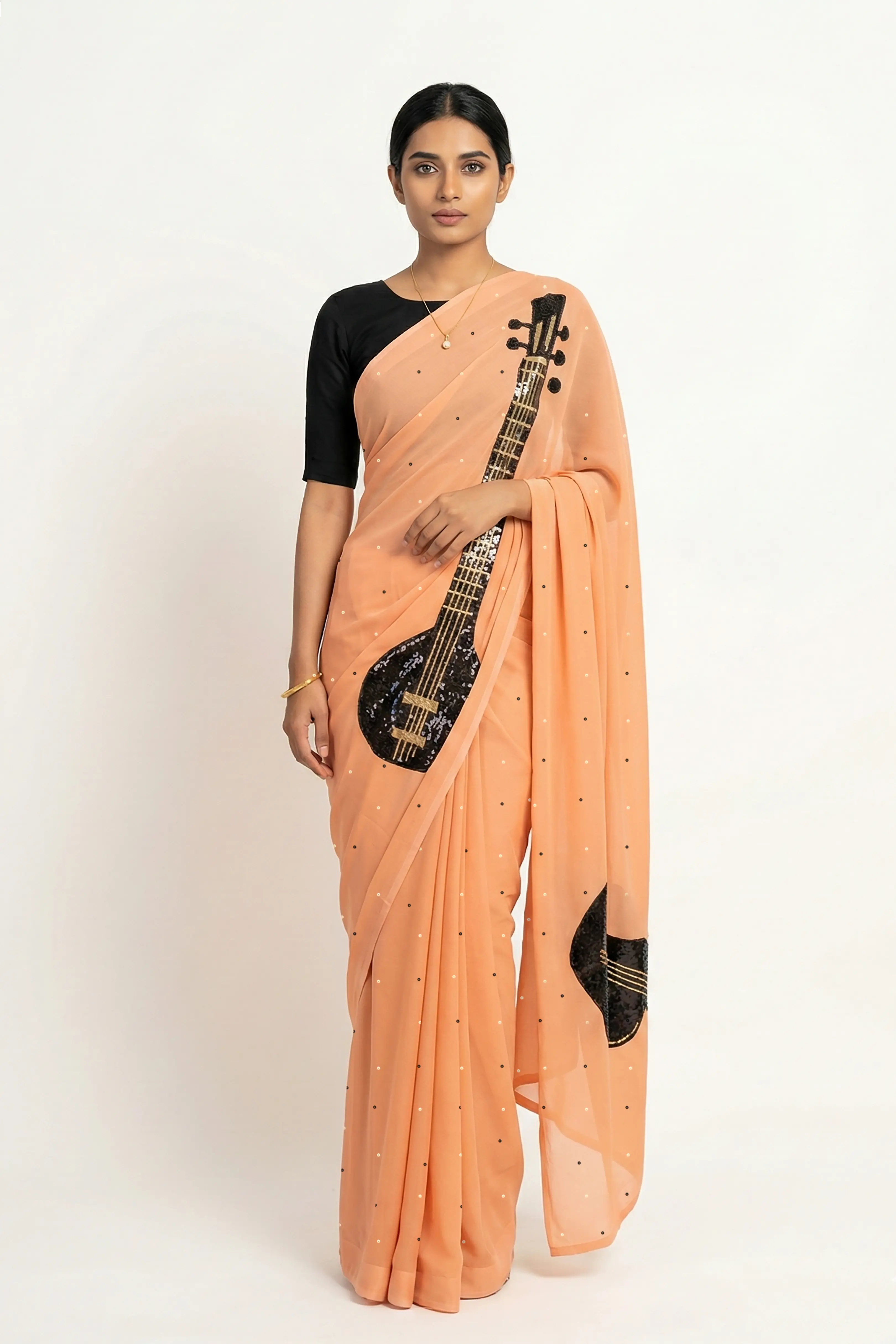 An Indian woman in peach Ragini Saree embellished  with Sitar Motifs made of Zari & sequins by craft of Aari-Zardosi, a product of Umaid Couture