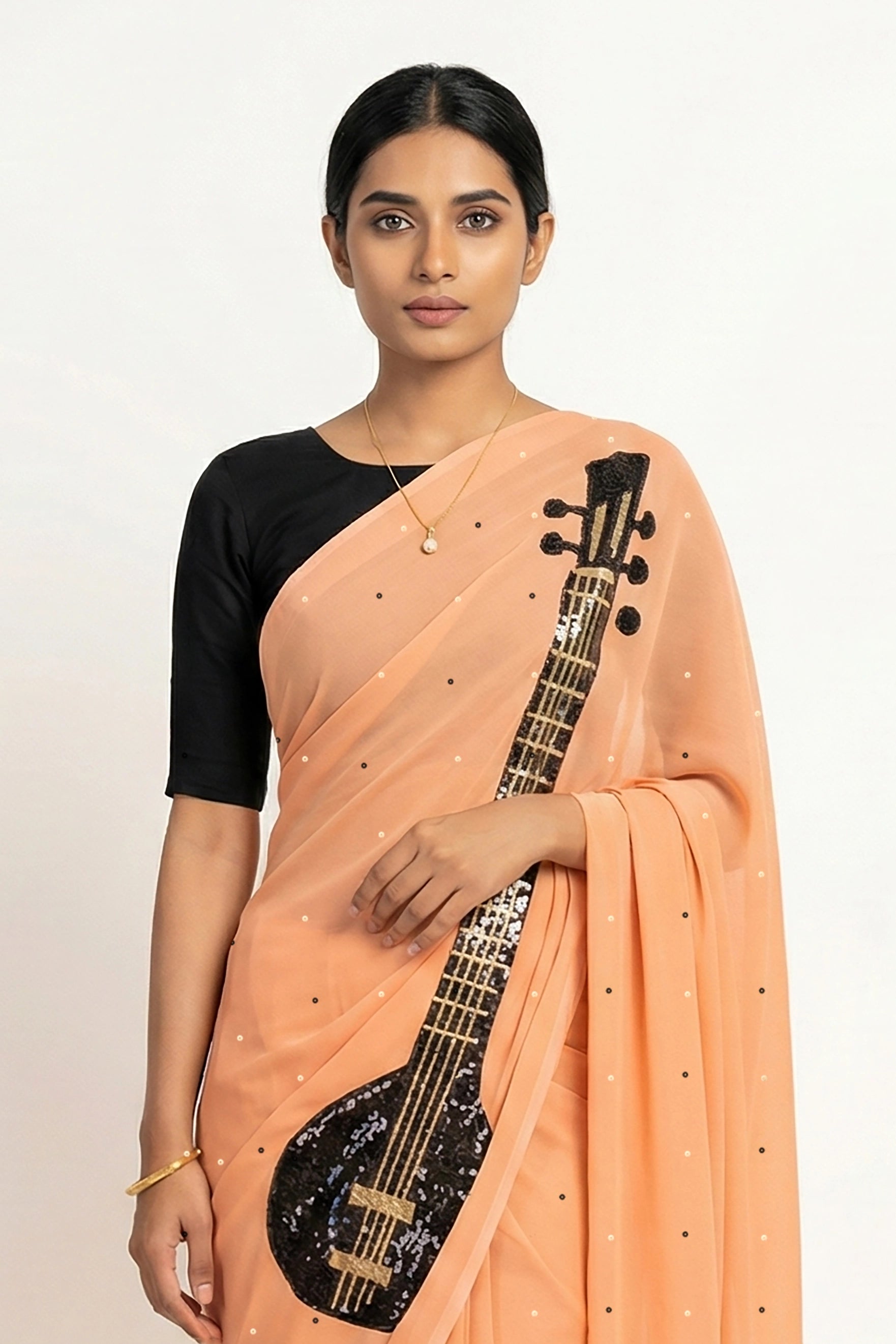 An Indian woman in peach Ragini Saree embellished  with Sitar Motifs made of Zari & sequins by craft of Aari-Zardosi, a product of Umaid Couture