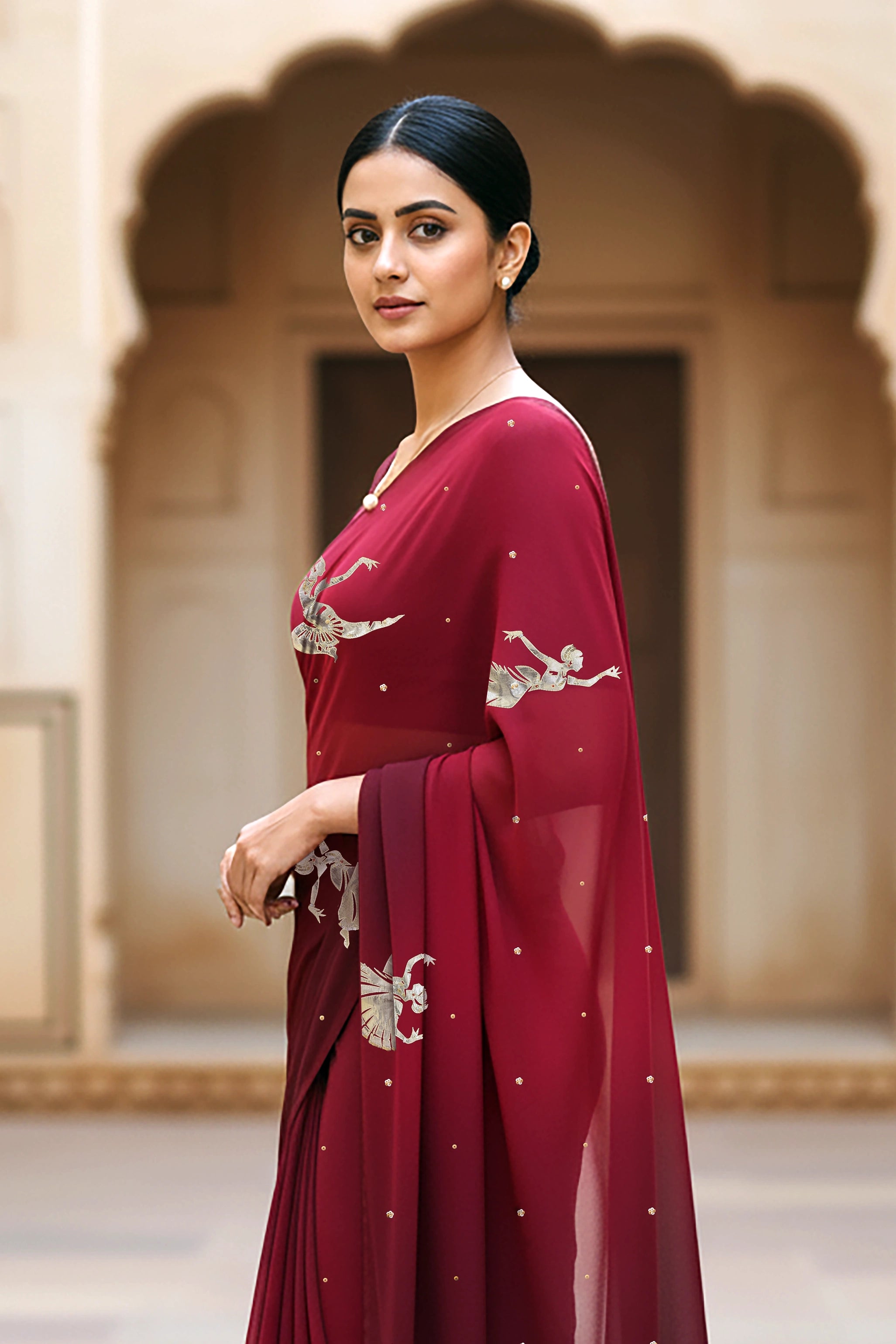 woman standing wearing wine red hue mulberry chiffon silk saree with kathak dance motifs on it designed bt umaid couture.