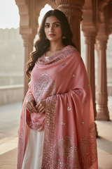 Woman wearing a traditional pastel pink  hand embroidered pashmina shawl in with sequins temple motifs standing in a corridor