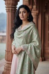 Woman wearing a pastel green shawl with pink sequins embroidery by Umaid Couture, standing in a corridor 