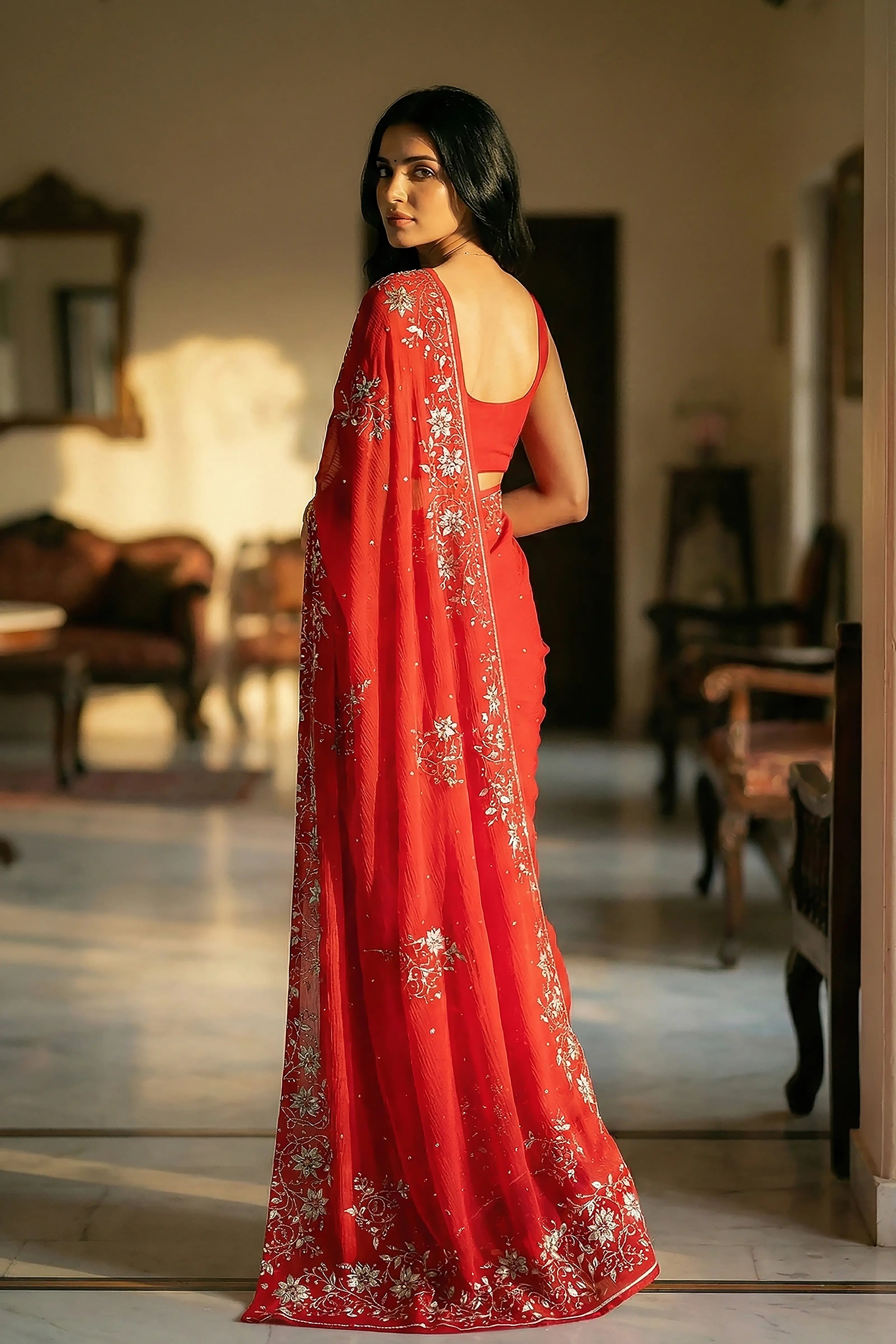 Woman in mulberry red saree with jasmine floral vines border on saree made by umaid couture.