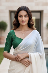 Woman wearing a green blouse and white saree with a blurred background. product by Umaid Couture