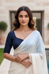 Woman wearing a white saree with a blue blouse in an outdoor setting. product by Umaid Couture