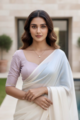 Woman wearing a light pink blouse and white saree with a blurred background. product by Umaid Couture