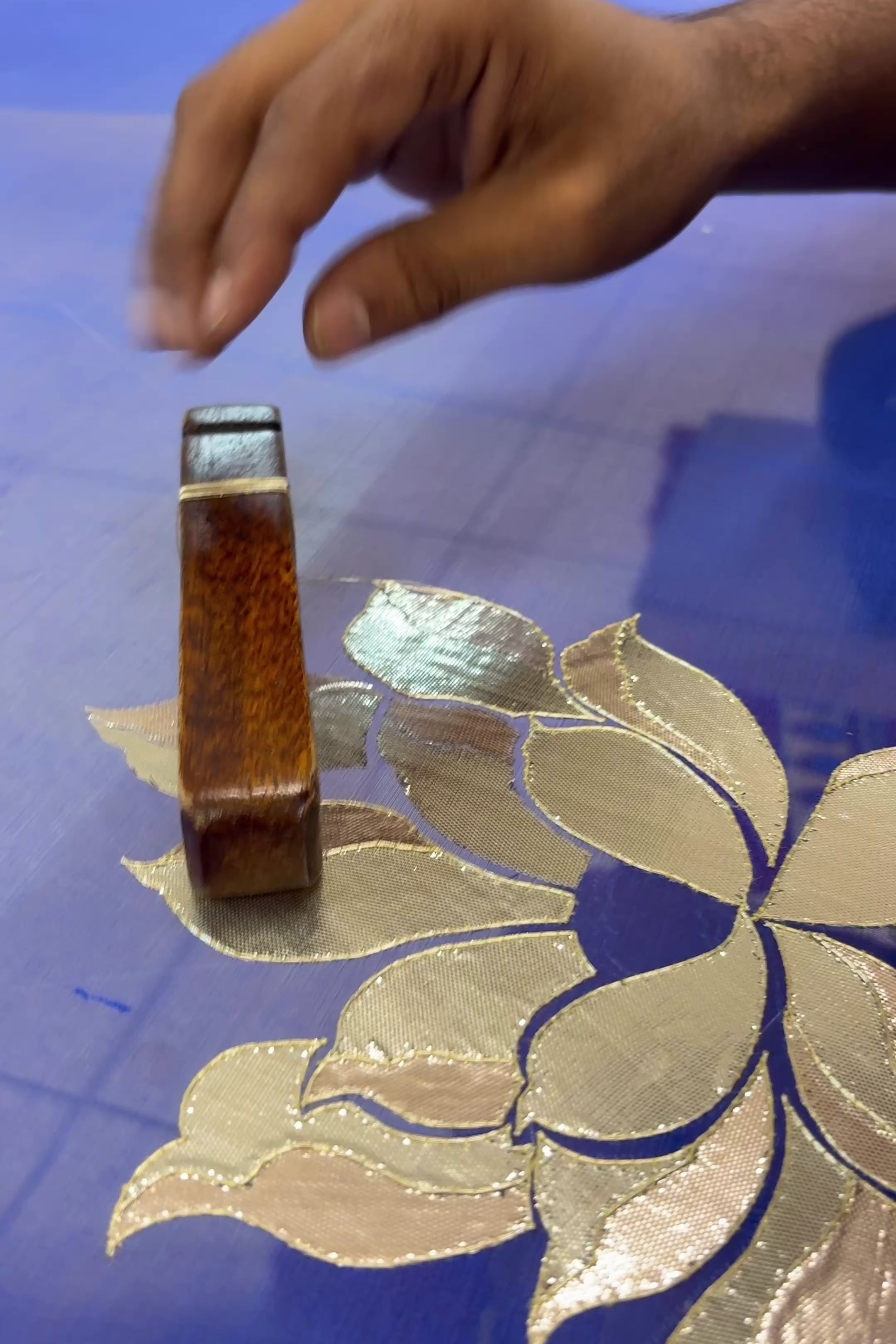 An Indian woman standing in a garden courtyard wearing blue chiffon saree embellished with large gota lotus flower motifs by Umaid Couture.  
