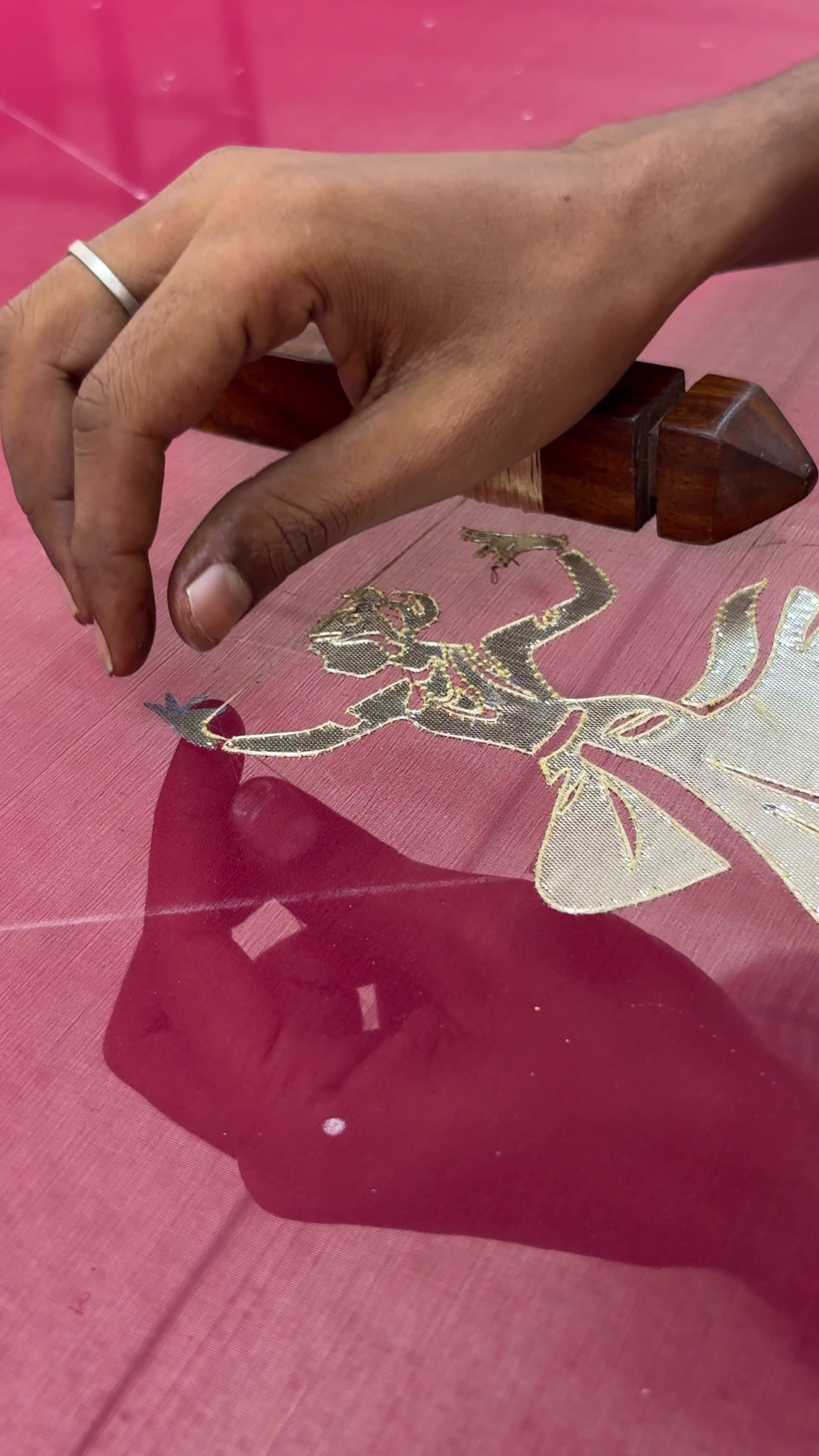 An Indian woman standing in a heritage  hotel courtyard wearing a wine red chiffon saree embellished with gold and sliver sequin of kathak dance motifs by Umaid Couture.  
