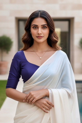 Woman wearing a white saree with a blue blouse in an outdoor setting. product by Umaid Couture