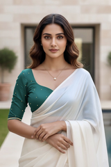 Woman wearing a green blouse and white saree with a blurred background. product by Umaid Couture