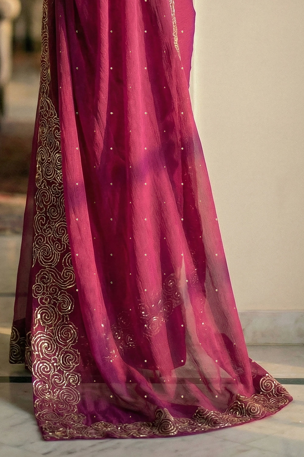 Woman in mulberry red saree with artistic cloud vines border on saree made by umaid couture.