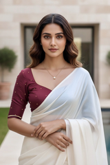 Woman wearing a white saree with a maroon blouse in an outdoor setting. product by Umaid Couture